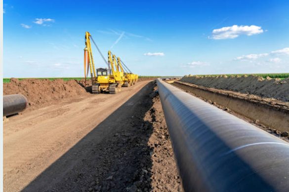 Sidebooms lowering a welded pipe string into the ditch on a Tucker spread