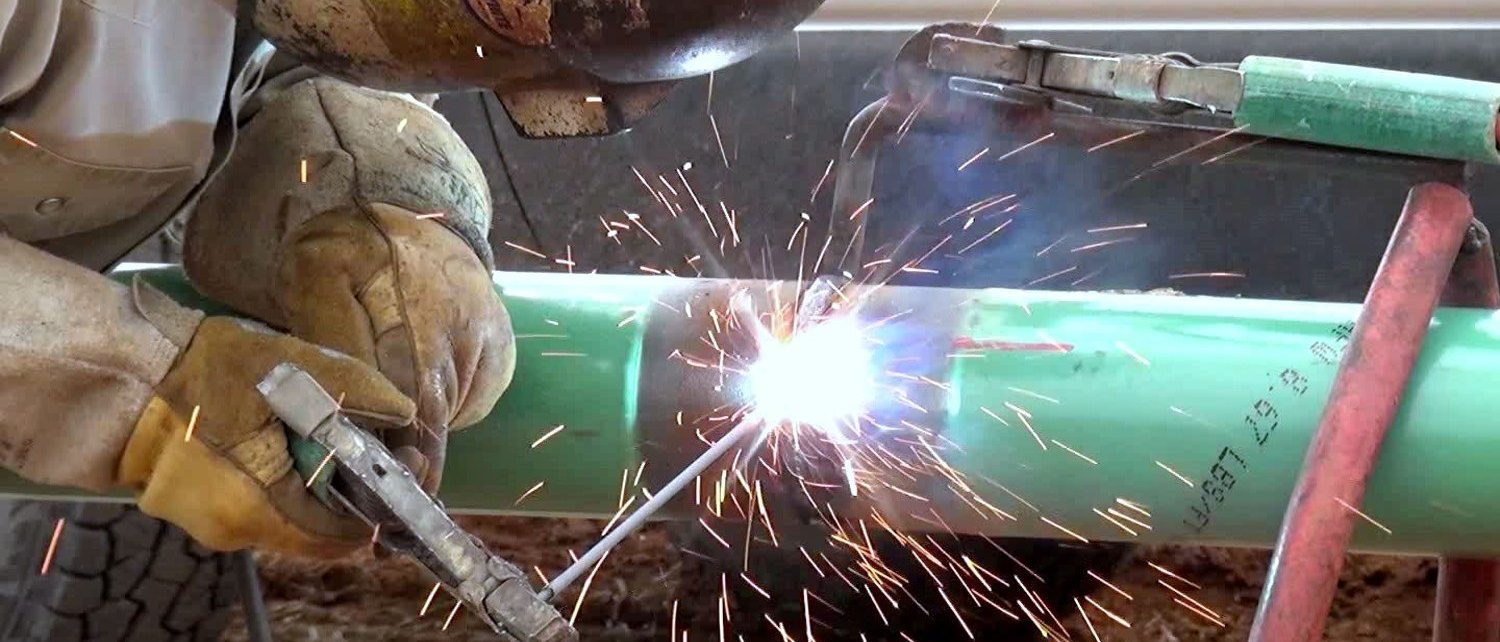 Tucker welder making a tie-in weld on coated pipe in the ditch